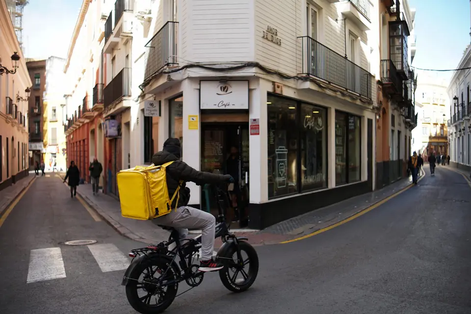 Mensajero en bicicleta con caja de domicilios recorriendo una calle