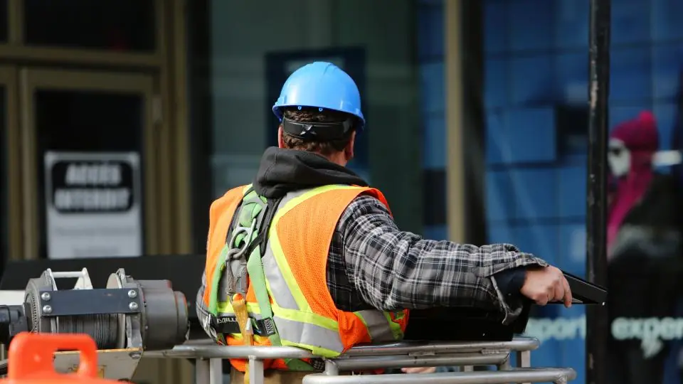 Technician in a high-visibility vest and hard hat operating equipment on the street