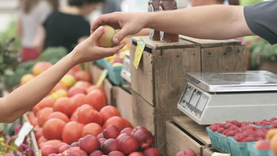 Vendor handing fruit to a customer at a market stall