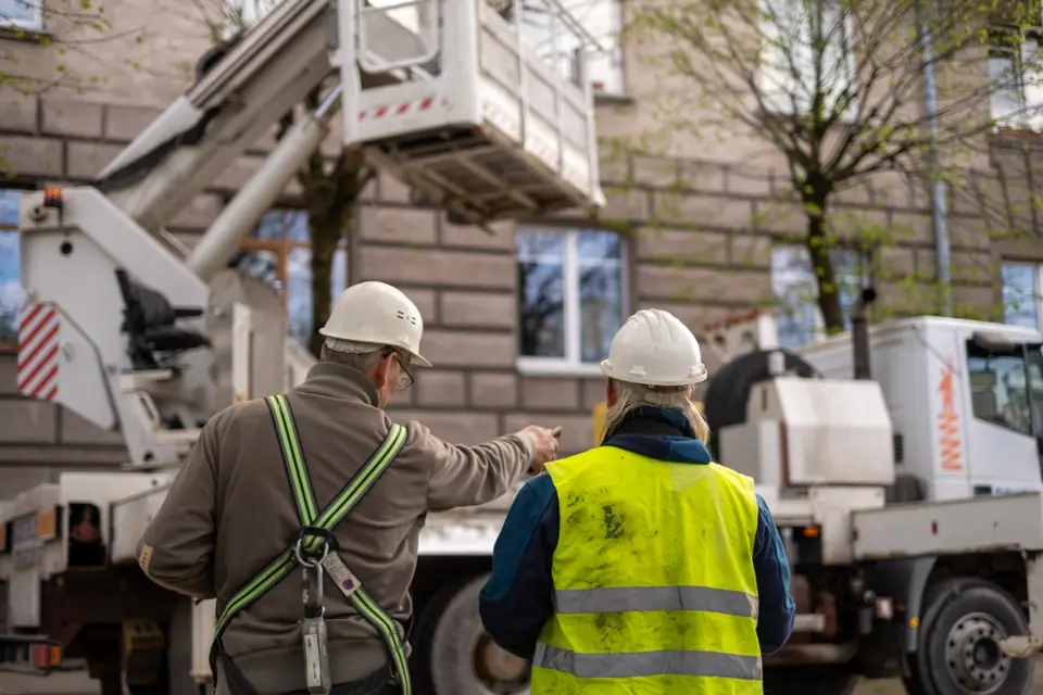 Technicians in hard hats coordinating an installation next to a crane truck
